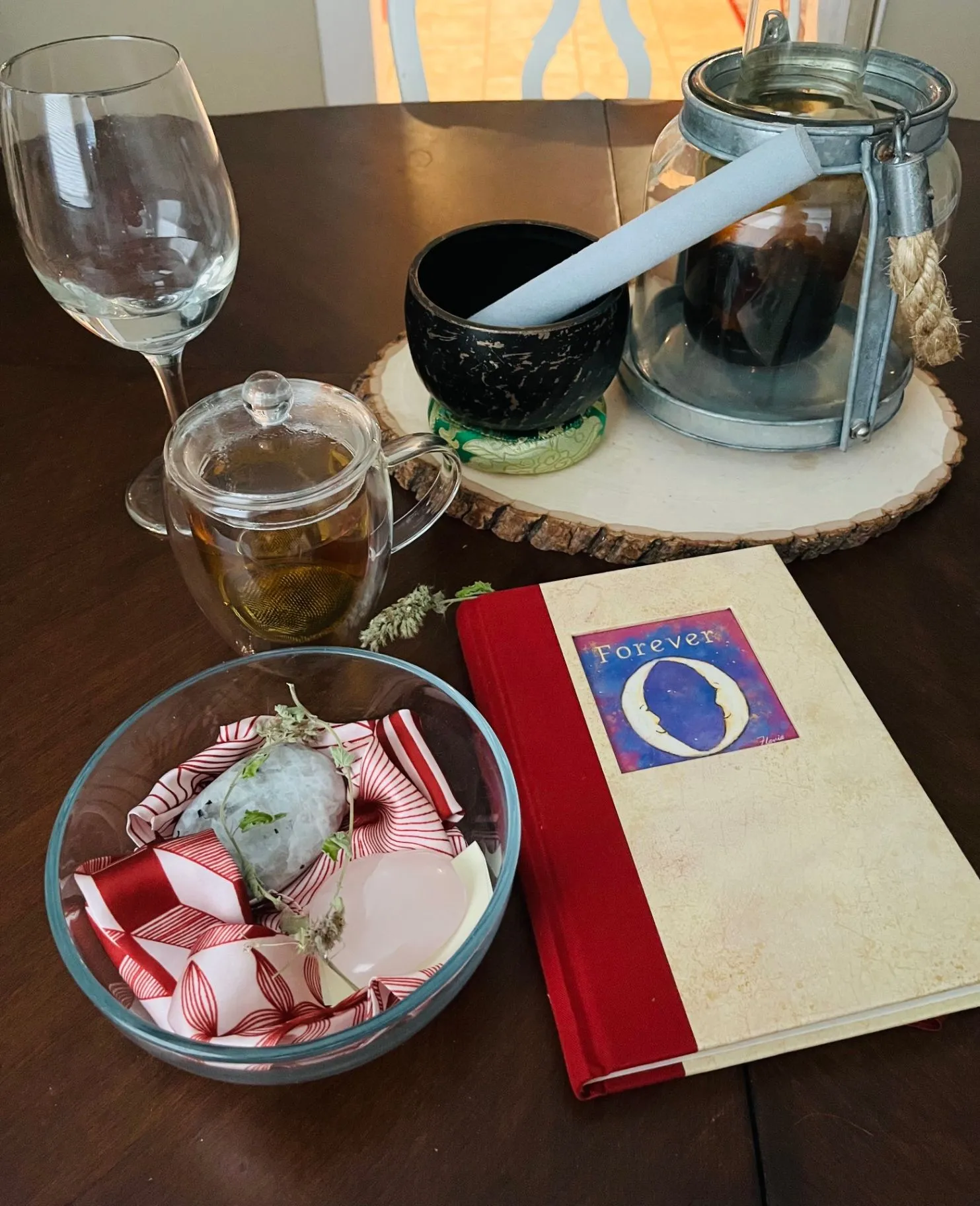 A warm ritual table with tea, a candle, a white smudge bundle, and crystals