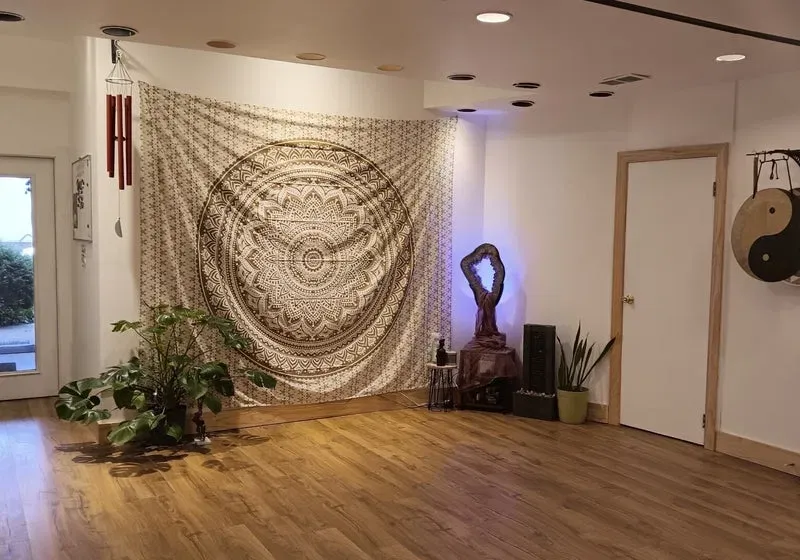 Violets in Bloom studio interior with warm wood floors, greenery, mandala art, a gong, and soft lighting
