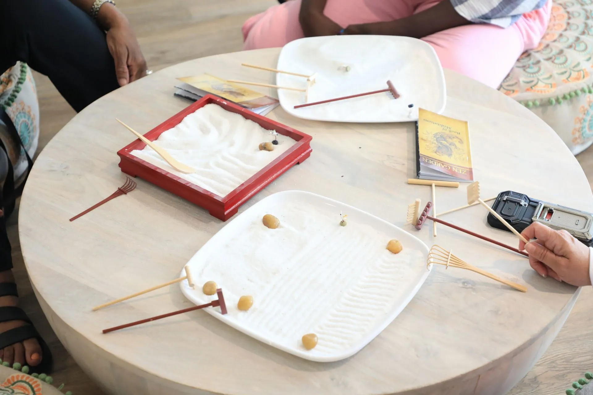 A small group gathered around a tabletop sand garden during a quiet meditation practice